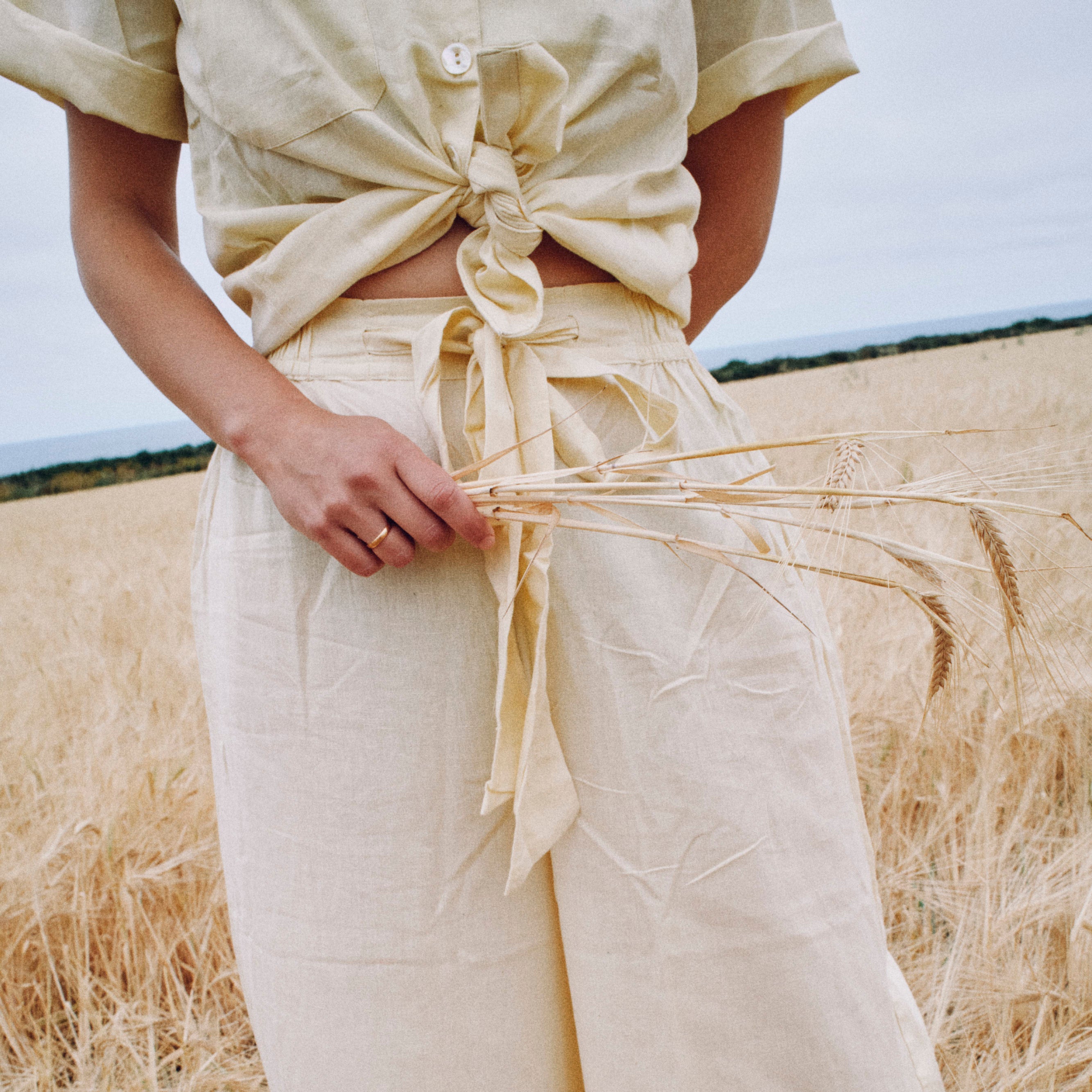 Person wearing a beige outfit standing in a field of tall grass.