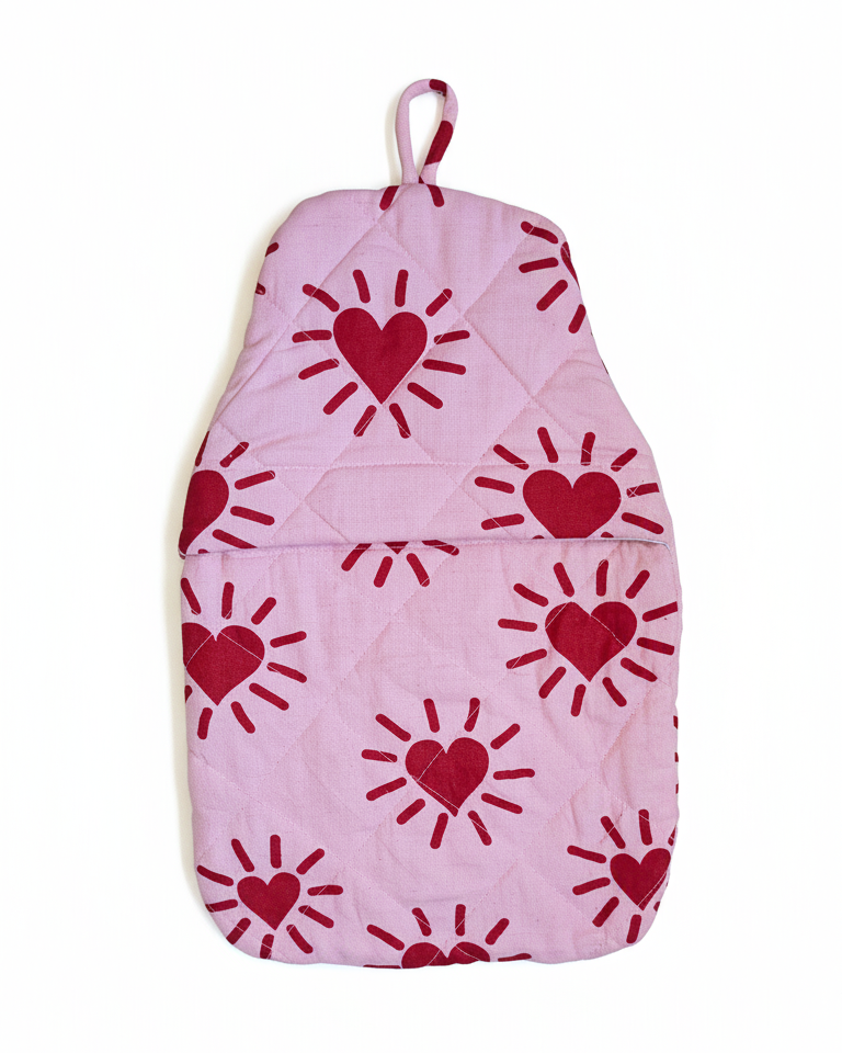 Red heart and sun like patterns on a pink quilted hot water bottle cover
